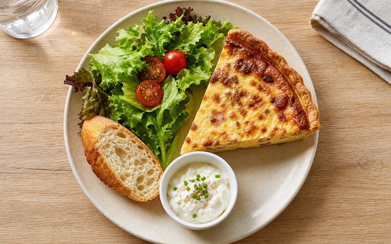 Assiette française vue de dessus avec quiche, salade, baguette et fromage frais